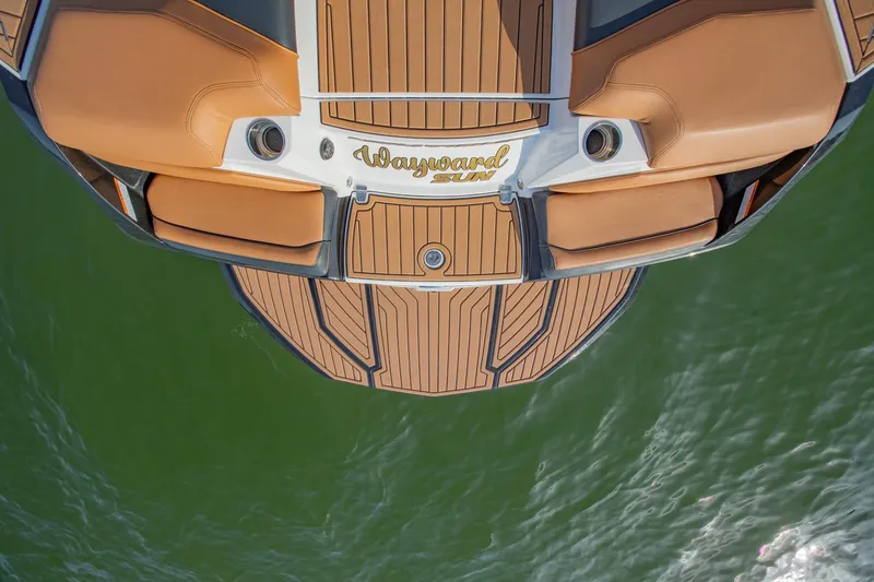 Slide: The Image of 2020 Nautique Super Air Nautique G25 boat deck, brown seating, on green water. - 9