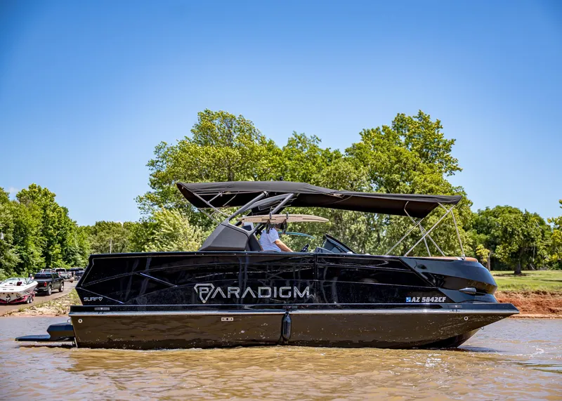 Slide: The Image of 2025 Paradigm 236 boat cruising on a sunny day, surrounded by lush greenery. - 2