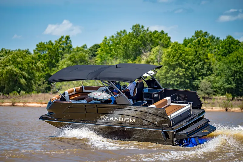 Slide: The Image of 2025 Paradigm 236 boat cruising on a lake with lush green trees in the background. - 9