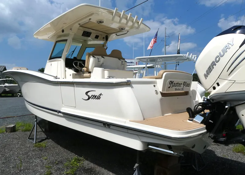 Slide: The Image of 2022 Scout 305 LXF boat with Mercury engine, displayed outdoors under a blue sky. - 2