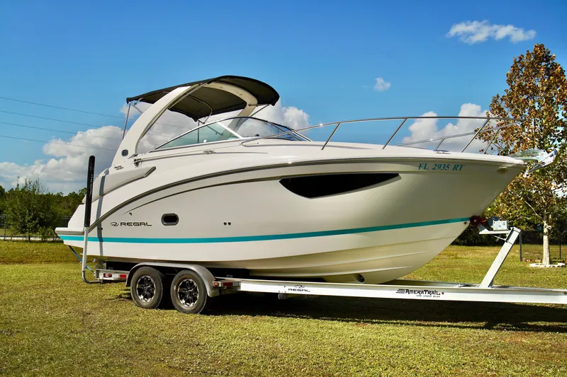 The Image of 2019 Regal 26 Express boat on trailer, parked on grass under clear blue sky. - 0