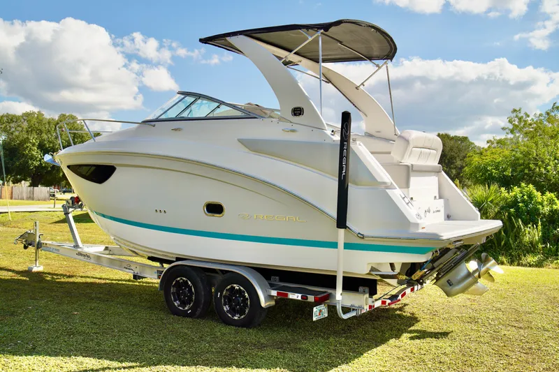 Slide: The Image of 2019 Regal 26 Express boat on trailer, parked on grass under a sunny sky. - 10