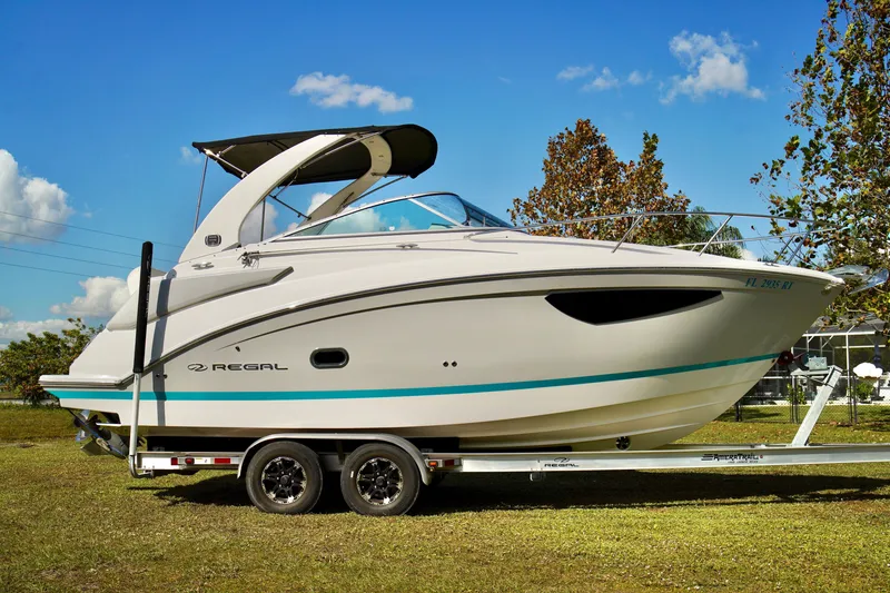 Slide: The Image of 2019 Regal 26 Express boat on trailer under clear blue sky. - 2