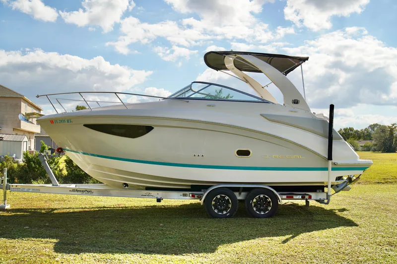 Slide: The Image of 2019 Regal 26 Express boat on trailer, parked on grass under a partly cloudy sky. - 3