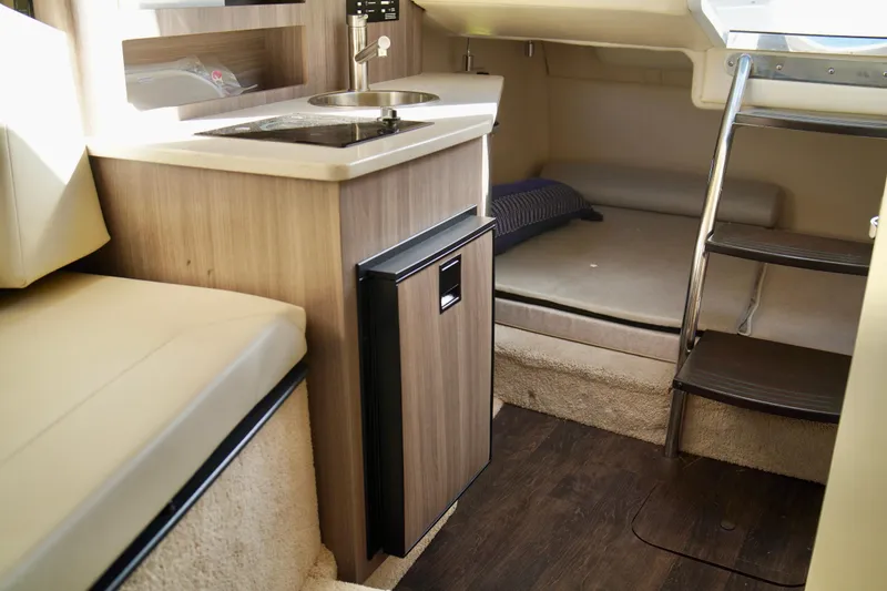 Slide: The Image of 2019 Regal 26 Express cabin interior with kitchenette, seating, and sleeping area. - 31