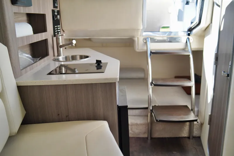 Slide: The Image of Interior of a 2019 Regal 26 Express boat with kitchenette and seating area. - 36