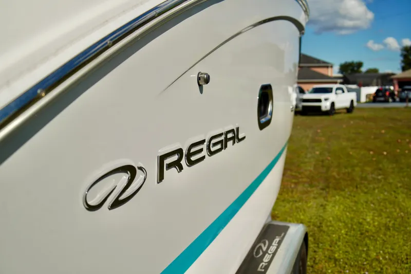 Slide: The Image of 2019 Regal 26 Express boat side view with logo, parked on grass. - 5