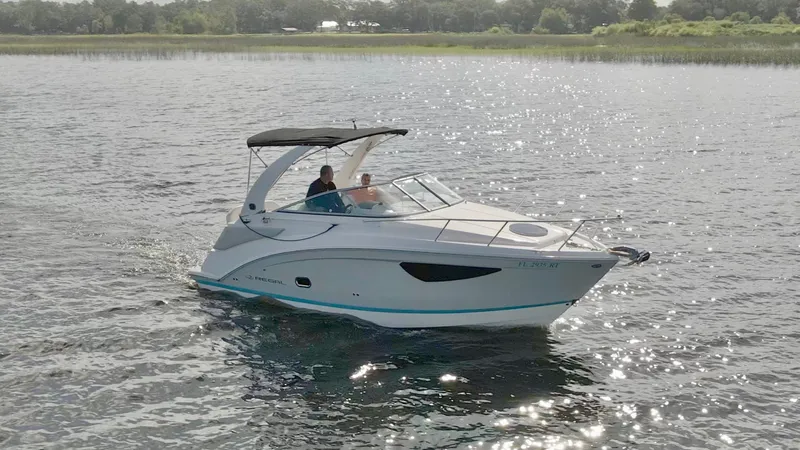 Slide: The Image of 2019 Regal 26 Express boat cruising on a sunny lake with two passengers. - 55