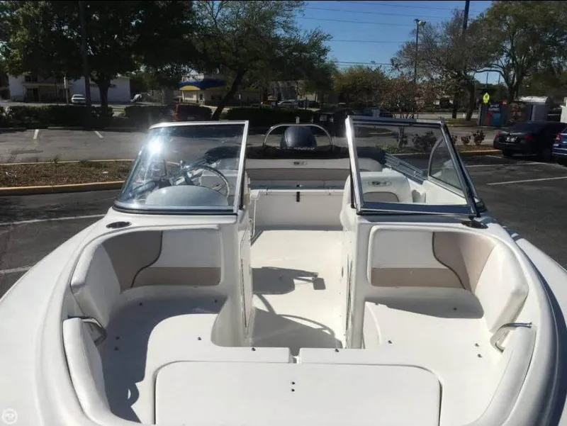 Slide: The Image of 2013 Sea Hunt Escape 188 boat interior with open seating and windshield in a parking lot. - 3