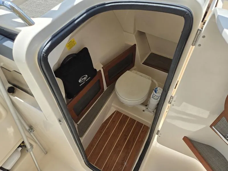 Slide: The Image of 2019 Grady-White Freedom 235 boat interior with compact marine toilet and wooden flooring. - 20