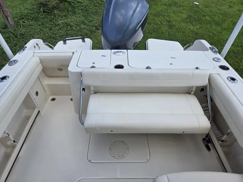 Slide: The Image of 2019 Grady-White Freedom 235 boat interior with seating and motor, on grassy background. - 7