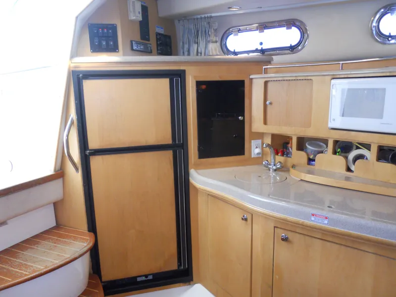 Slide: The Image of Interior of 2000 Boston Whaler 34 Defiance, featuring kitchenette with cabinets and appliances. - 32