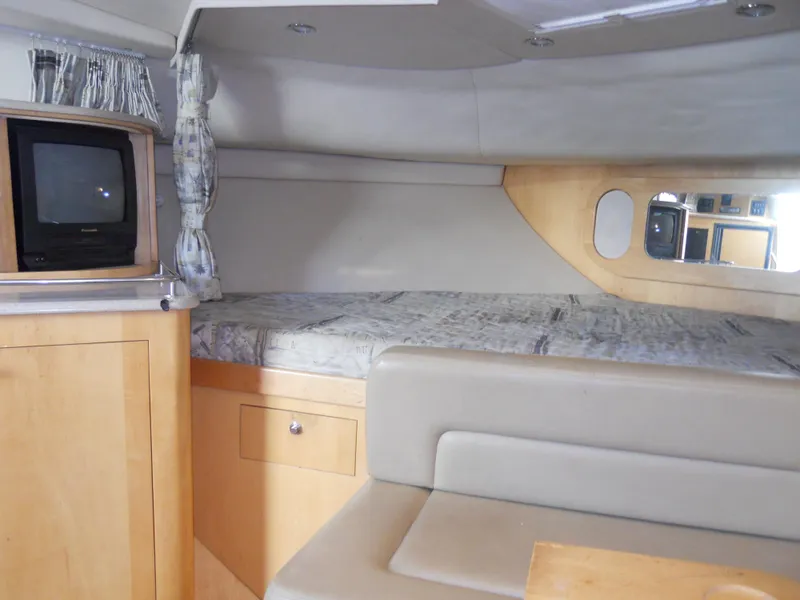 Slide: The Image of Interior of 2000 Boston Whaler 34 Defiance, featuring cozy cabin with bed and TV. - 34