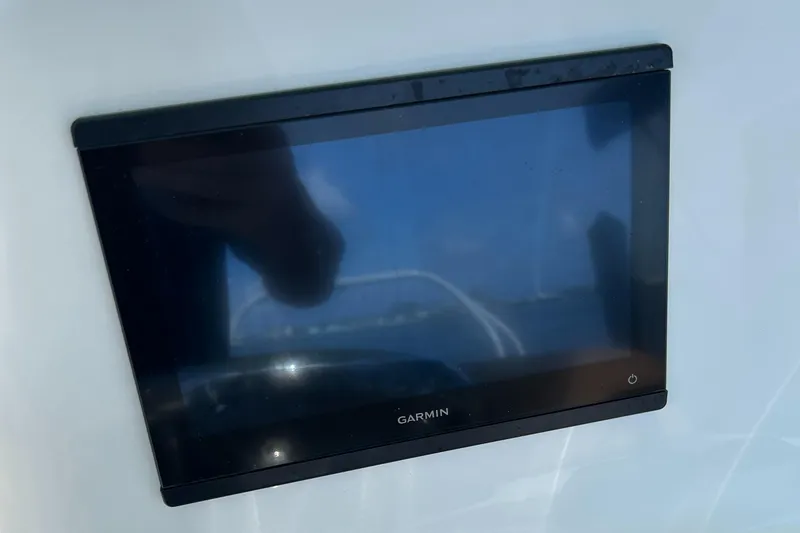 Slide: The Image of 2023 NauticStar 231 Hybrid boat interior with steering console and seating, docked near waterfront homes. - 15