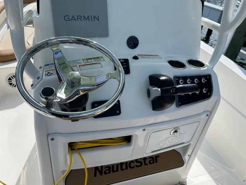 Slide: The Image of 2023 NauticStar 231 Hybrid boat with T-top and rod holders, docked under blue sky. - 16