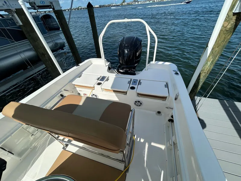 Slide: The Image of 2023 NauticStar 231 Hybrid boat seat with tan and beige cushions, docked by water. - 36