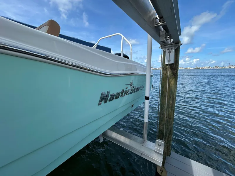 Slide: The Image of 2023 NauticStar 231 Hybrid boat motor in water, showcasing sleek design and propeller. - 54