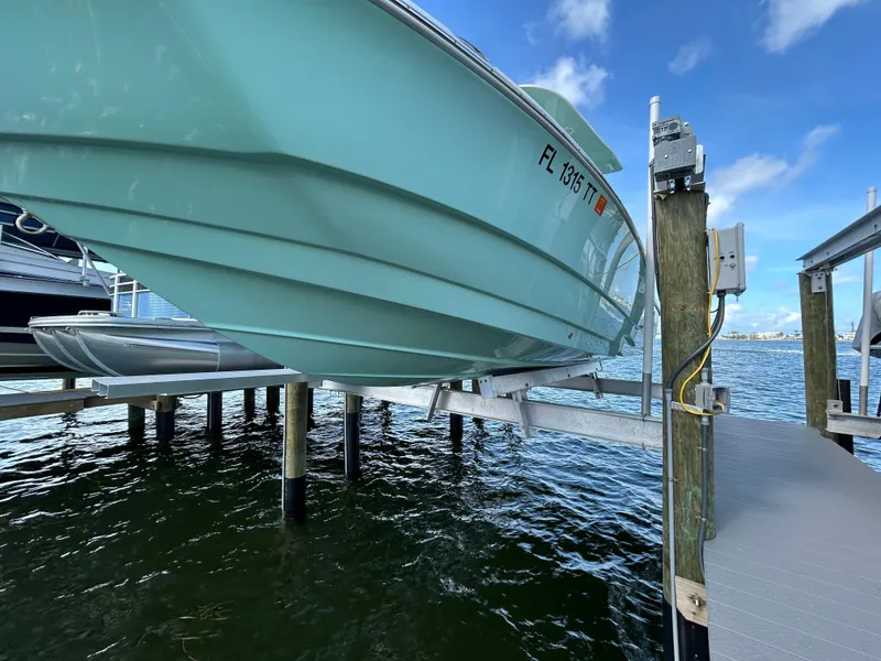 Slide: The Image of NauticStar 231 Hybrid 2023 on boat lift over water. - 56