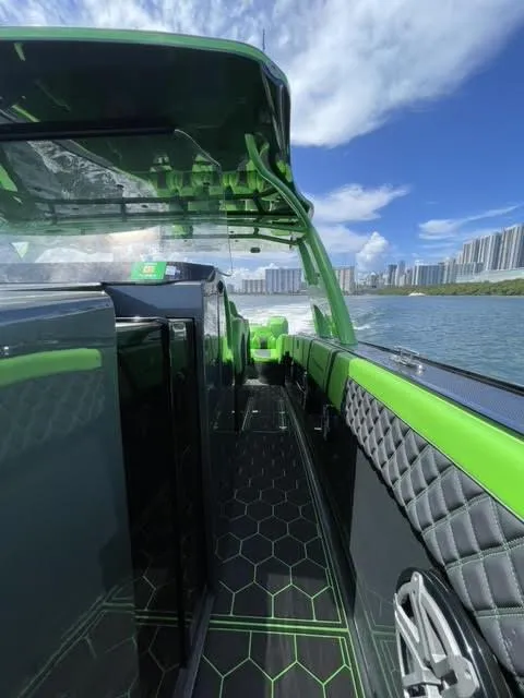 Slide: The Image of 2020 Midnight Express Open 43 boat with green accents cruising on water, city skyline in background. - 7