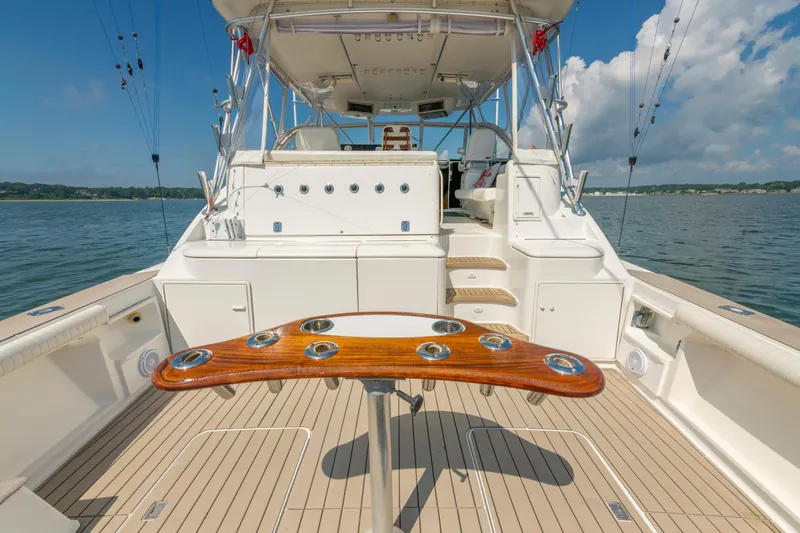 Slide: The Image of 1999 Ocean Yachts 48 Express boat deck with fishing rod holders, on calm water. - 13
