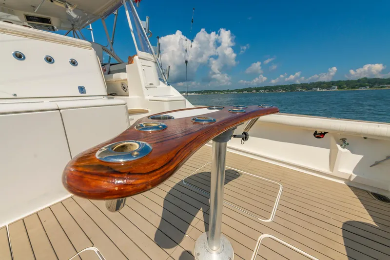 Slide: The Image of 1999 Ocean Yachts 48 Express deck with rod holders, overlooking serene waters and blue sky. - 14