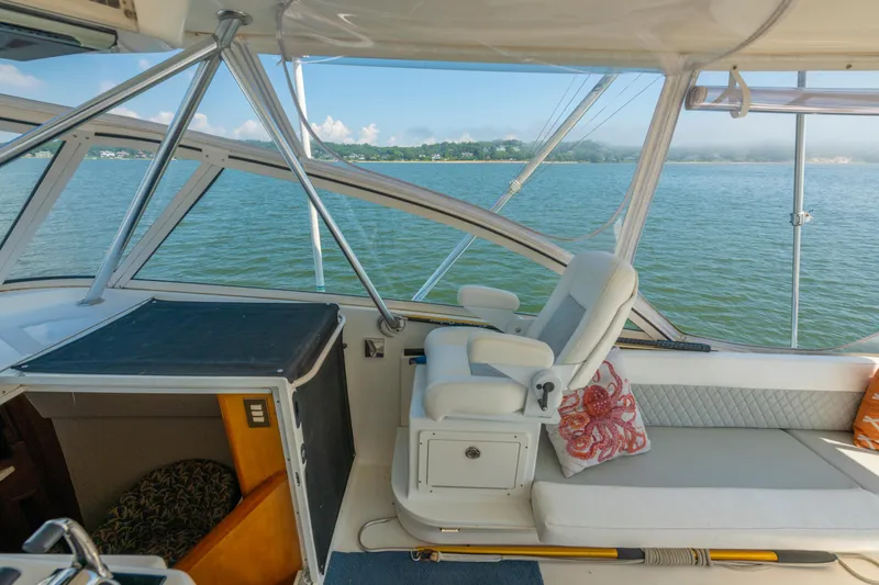 Slide: The Image of 1999 Ocean Yachts 48 Express interior with white seating, overlooking serene water and distant shoreline. - 28