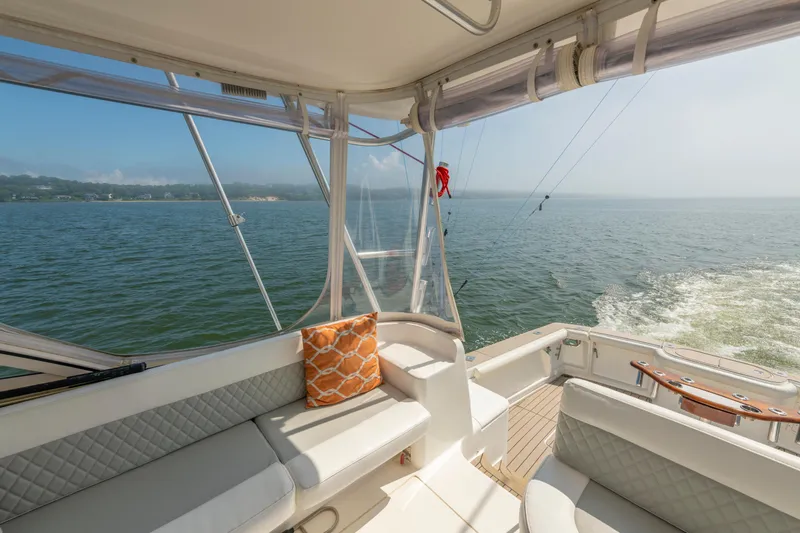 Slide: The Image of 1999 Ocean Yachts 48 Express interior with ocean view, featuring comfortable seating and orange pillow. - 30