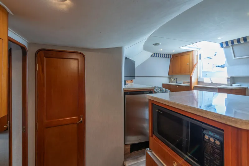 Slide: The Image of Interior of 1999 Ocean Yachts 48 Express, featuring kitchen area with microwave and wooden cabinetry. - 45