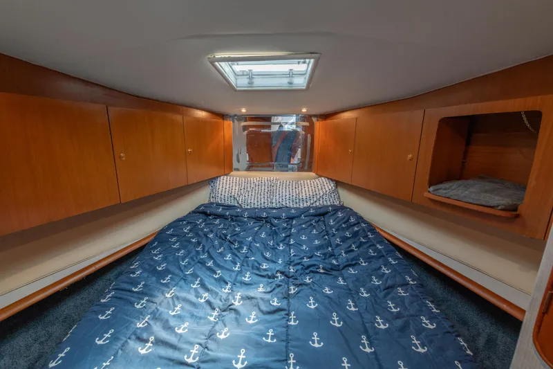 Slide: The Image of 1999 Ocean Yachts 48 Express cabin with wooden cabinets and anchor-patterned bedding. - 48