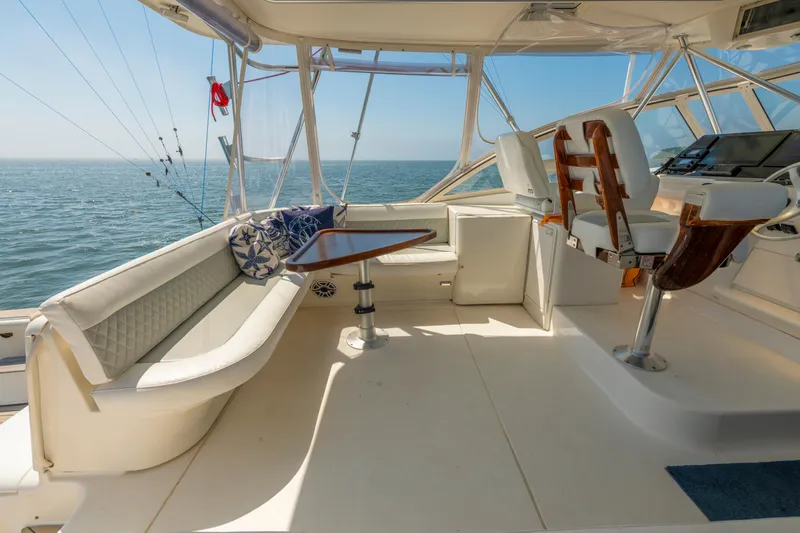 Slide: The Image of 1999 Ocean Yachts 48 Express interior with seating, table, and helm, overlooking the ocean. - 25