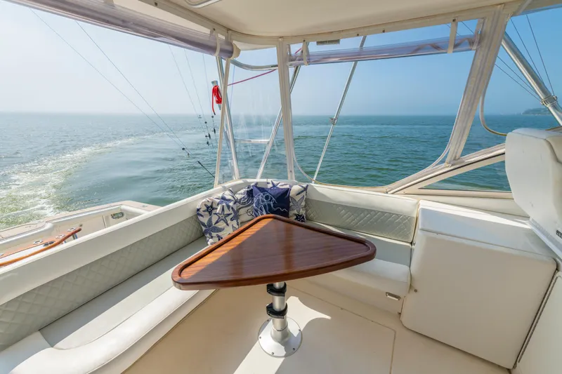 Slide: The Image of 1999 Ocean Yachts 48 Express interior with ocean view, featuring a cozy seating area and wooden table. - 26