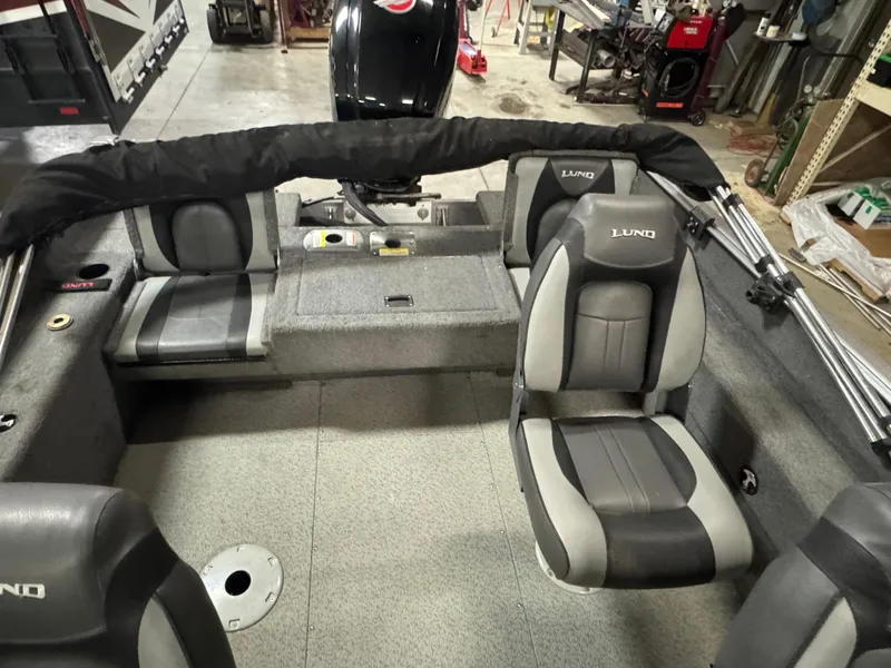 Slide: The Image of 2017 Lund 1850 Impact XS boat interior with seating and motor in a garage setting. - 11