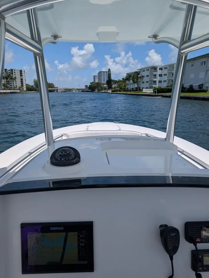 Slide: The Image of 2016 Southport 272TE boat navigating a scenic waterway with clear skies and buildings in view. - 12
