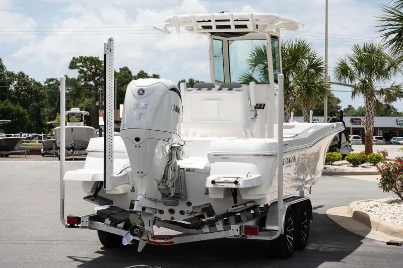 Slide: The Image of 2026 Caymas 24 HB boat with Yamaha engine on a trailer, parked outdoors. - 6