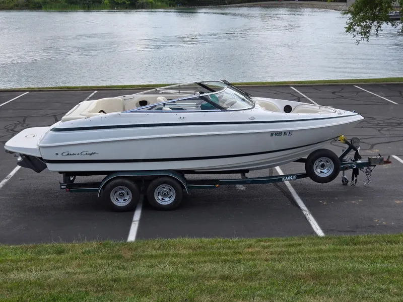 The Image of 1998 Chris-Craft 210 Bowrider on trailer by a scenic lake. - 0