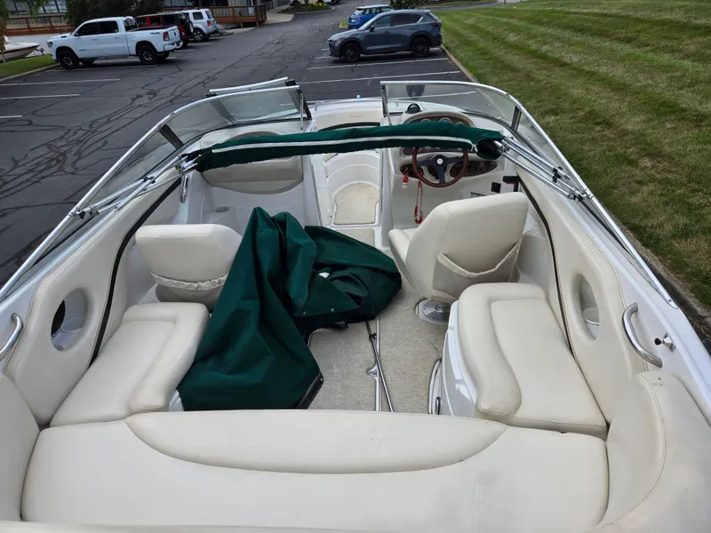 Slide: The Image of 1998 Chris-Craft 210 Bowrider interior with beige seating and steering wheel, parked outdoors. - 10