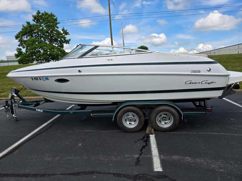 Slide: The Image of 1998 Chris-Craft 210 Bowrider on trailer, parked outdoors under clear blue sky. - 4