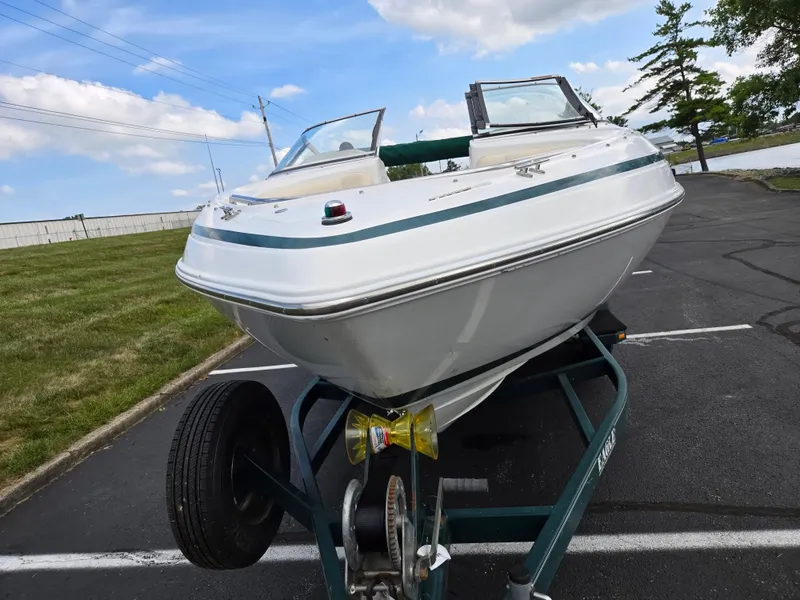 Slide: The Image of 1998 Chris-Craft 210 Bowrider on trailer by a lake, under clear blue sky. - 6