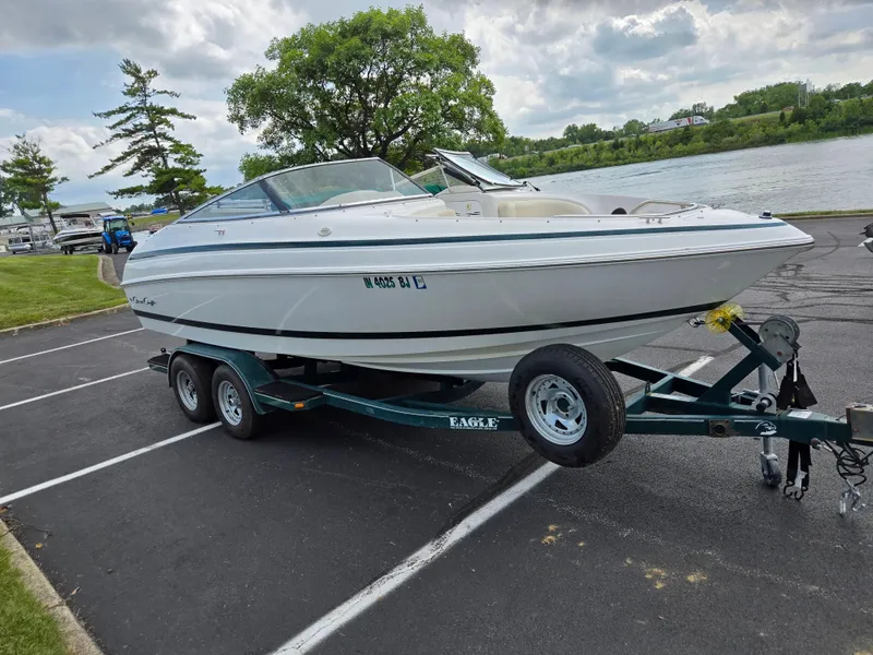 Slide: The Image of 1998 Chris-Craft 210 Bowrider on trailer by a lake, clear blue sky. - 8
