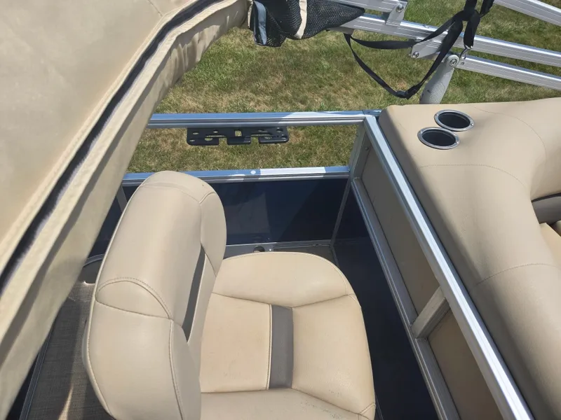 Slide: The Image of 2023 Sun Tracker Bass Buggy 18 DLX interior with beige seating and cup holders. - 17