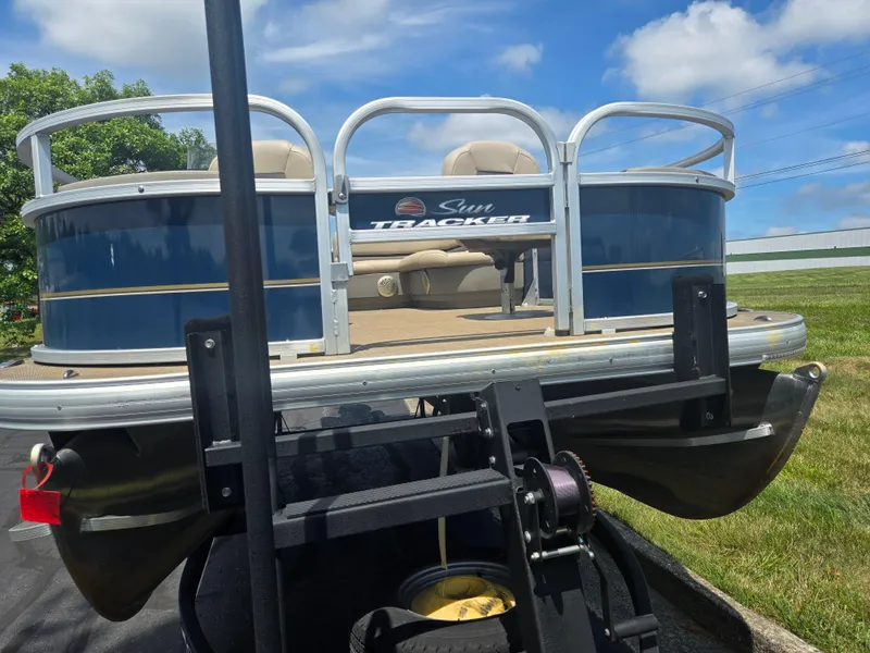 Slide: The Image of 2023 Sun Tracker Bass Buggy 18 DLX pontoon boat on trailer, blue and beige design. - 6