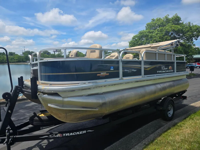 Slide: The Image of 2023 Sun Tracker Bass Buggy 18 DLX pontoon boat on trailer by a lake. - 8