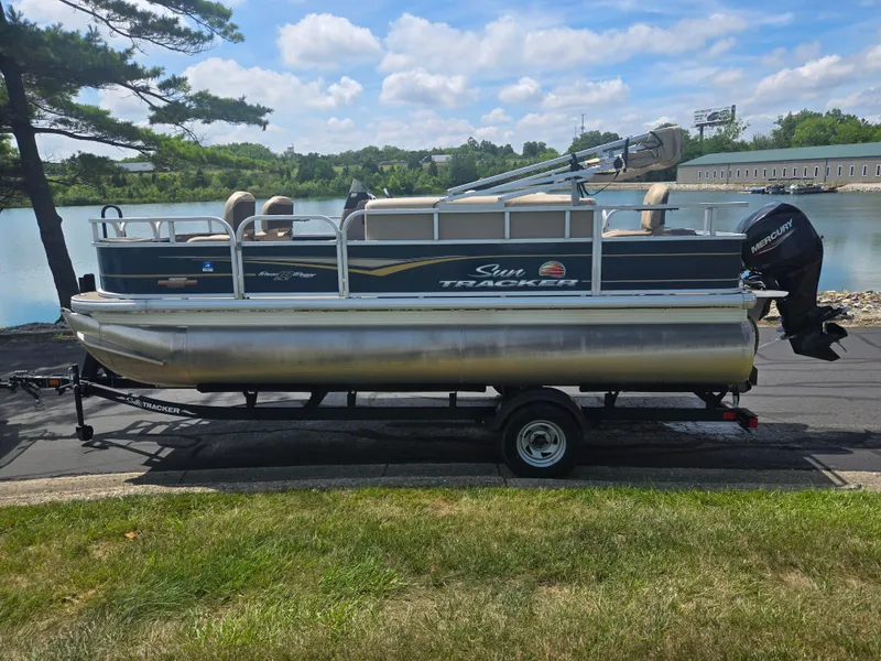 Slide: The Image of 2023 Sun Tracker Bass Buggy 18 DLX pontoon boat on trailer by a lake. - 9