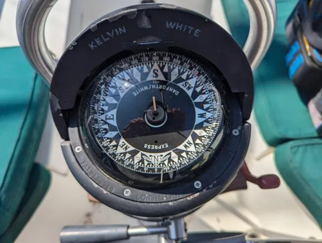 Slide: The Image of Compass on 1979 Sabre 28-2 sailboat, showing cardinal directions with green seating in background. - 16