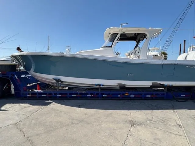 The Image of 2023 Edgewater 370 boat on trailer under clear blue sky. - 1