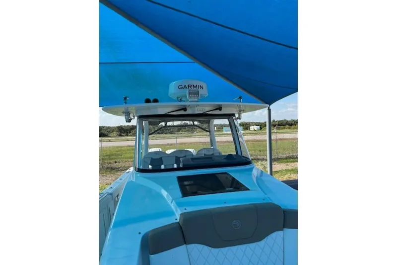 Slide: The Image of 2023 Edgewater 370CC boat under blue canopy with Garmin equipment visible. - 12