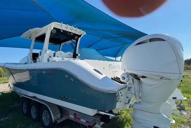 Slide: The Image of 2023 Edgewater 370CC boat on trailer under blue canopy. - 20