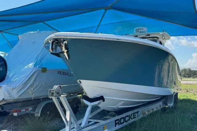Slide: The Image of 2023 Edgewater 370CC boat on trailer under blue canopy. - 22