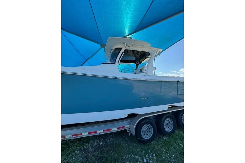 Slide: The Image of 2023 Edgewater 370CC boat on trailer under blue canopy. - 23