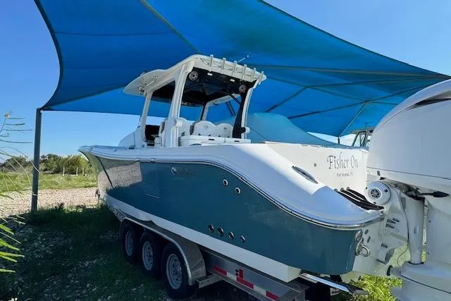 Slide: The Image of 2023 Edgewater 370CC boat on trailer under blue canopy. - 24